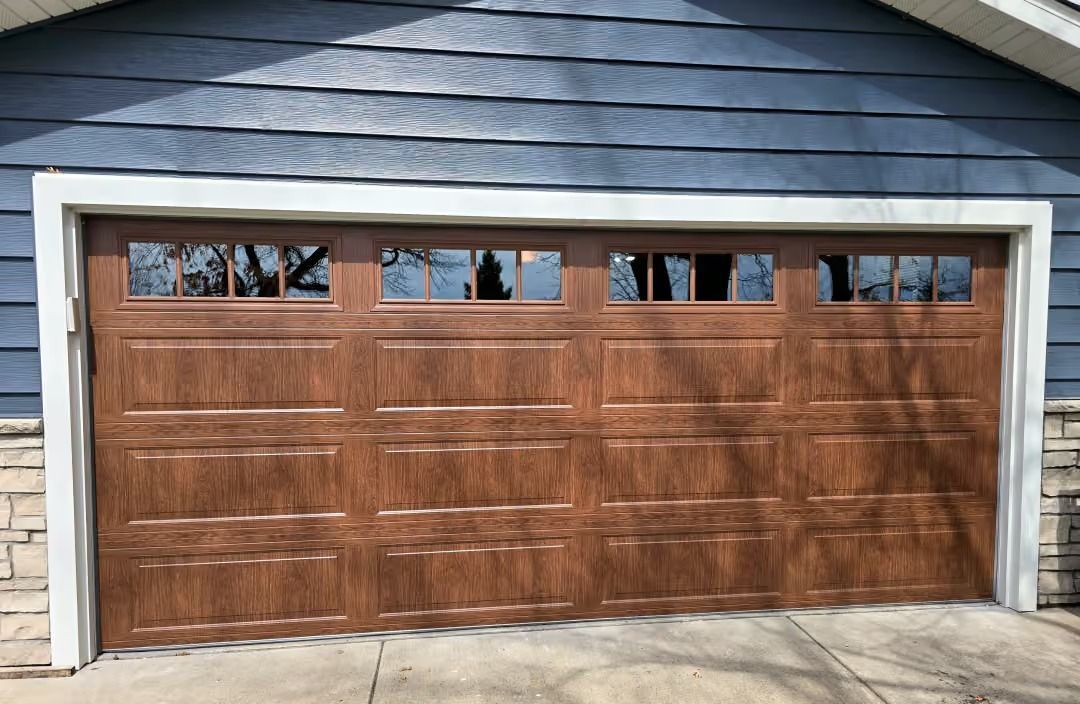 Wooden two-car garage door with small upper windows on a stone house exterior