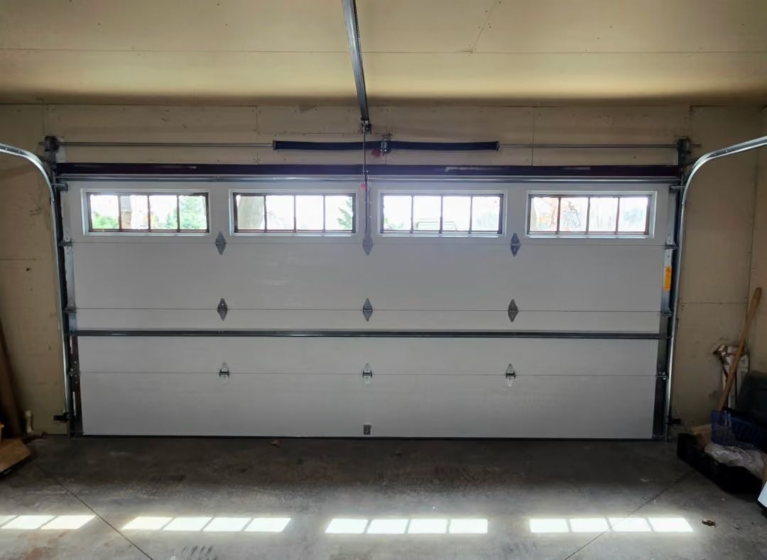 Closed white garage door with small windows in a garage interior