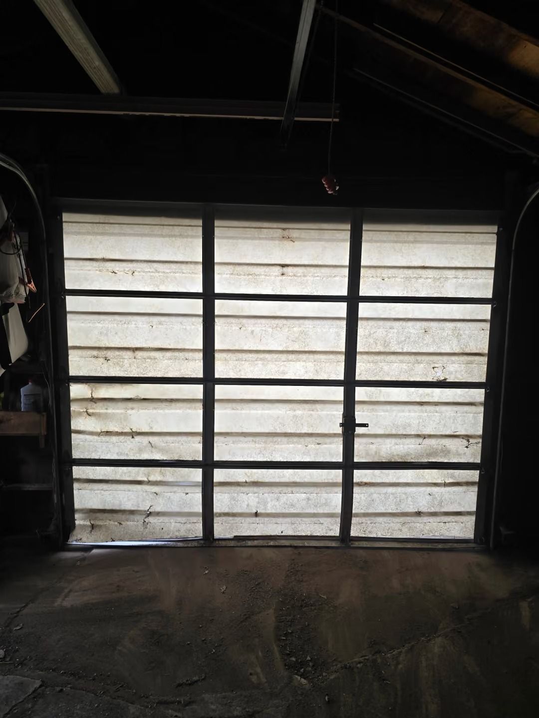 Dim garage interior with a frosted panel garage door and dark concrete floor.