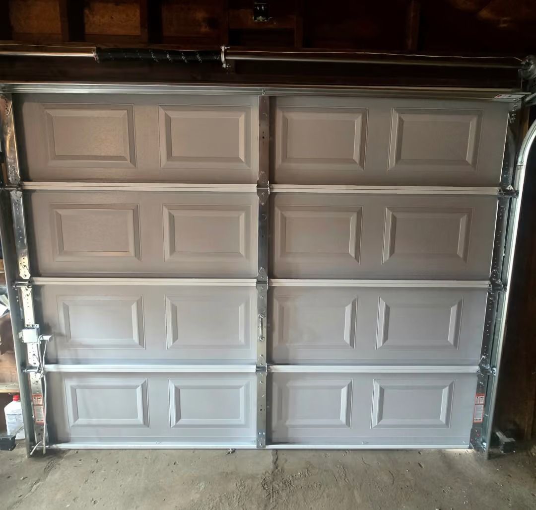 Closed white paneled garage door in a dimly lit garage opening