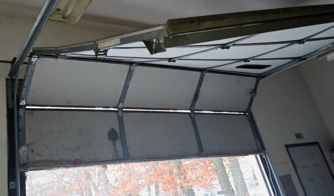 Open garage door with metal tracks and window panels, partially raised inside a garage.