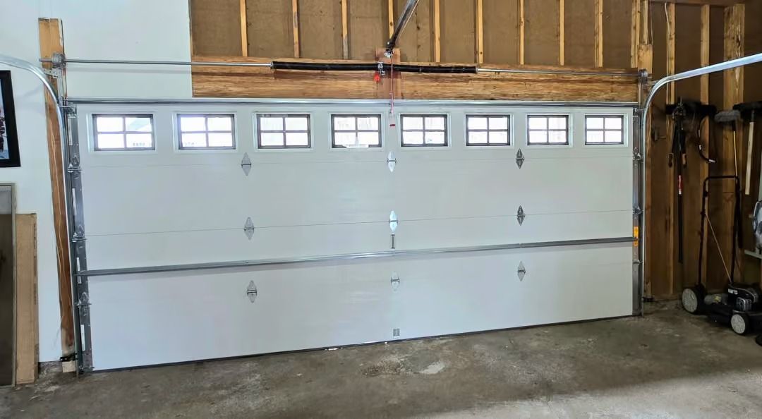 White double garage door with small windows in an unfinished indoor garage space