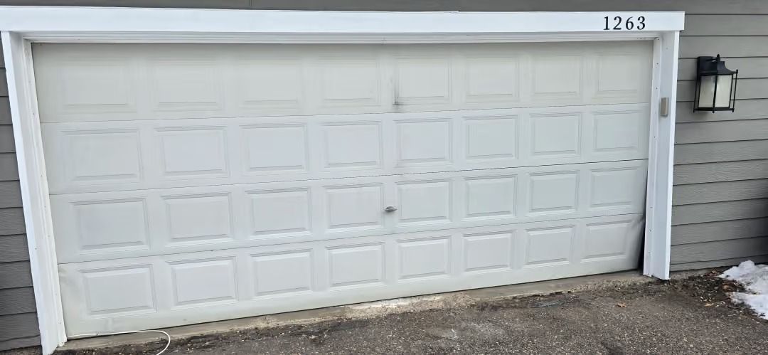 White double garage door with house number 1763 above it and a wall-mounted light on the right