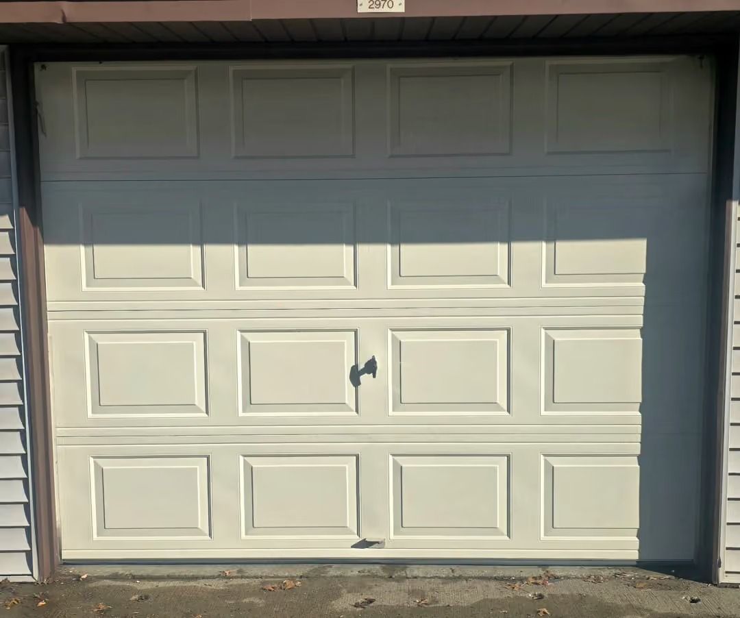 White garage door with dent and black paint mark near the center, set in a garage opening.