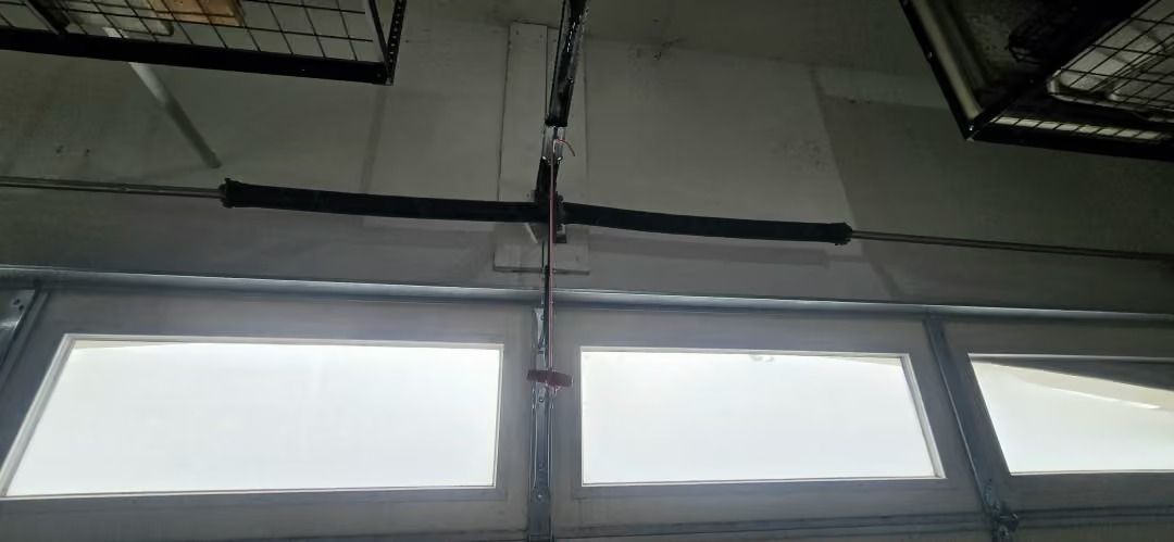 Ceiling view of three frosted windows beneath a black metal frame and hanging cable.