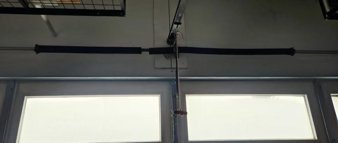Ceiling-mounted garage door opener above frosted windows in a dim room