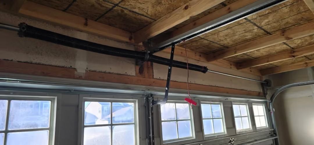 Ceiling beams and windows in an unfinished interior space, with insulation and exposed framing.