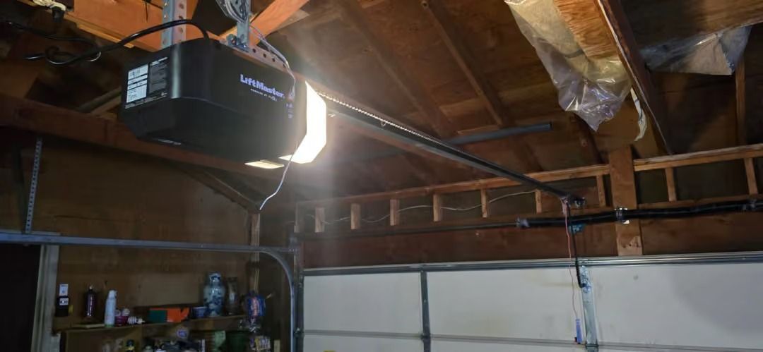 Interior of a garage with exposed rafters, a bright hanging light, and a sectional garage door below.