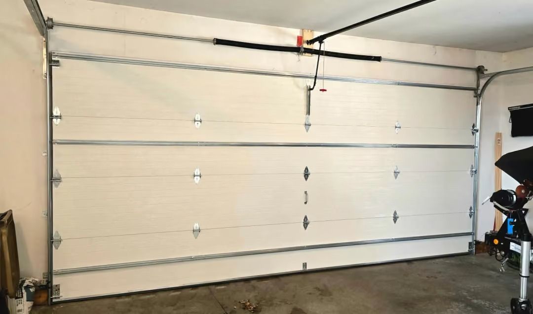 White garage door with four panels and a black opener rail in a garage interior.