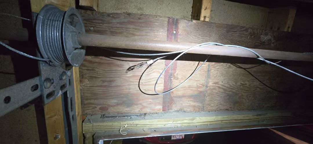 Wooden beam with exposed wiring and a spool in a dim attic or crawlspace