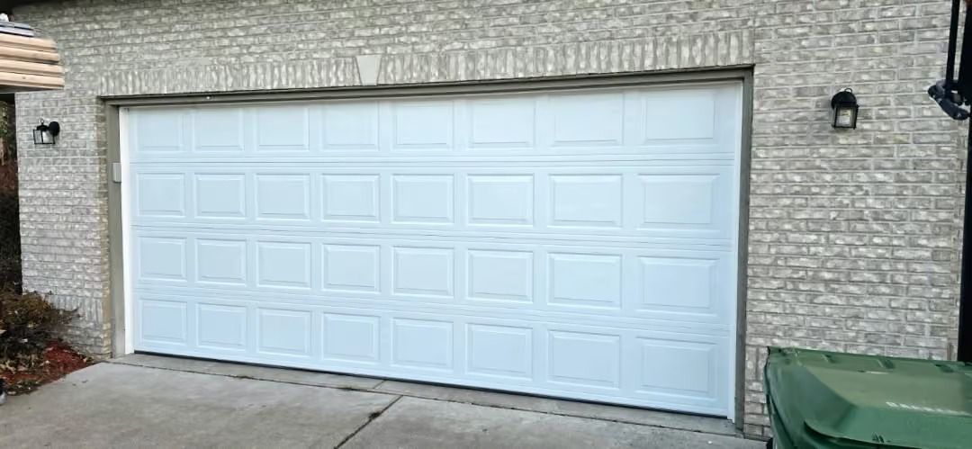 White double garage door on a stone house with a driveway in front