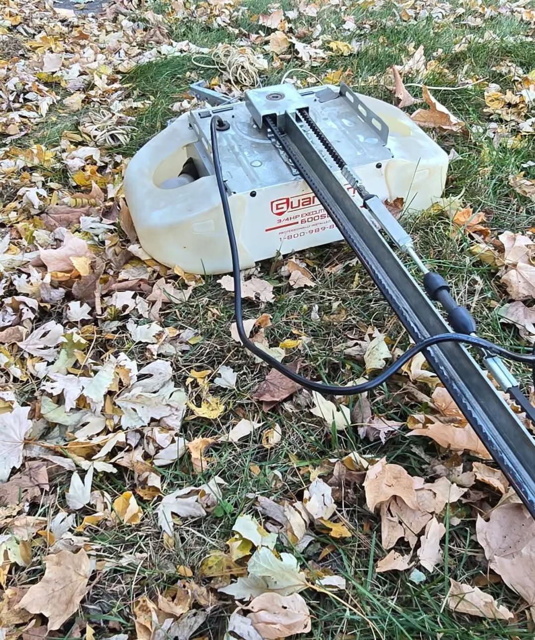 White sled on leaf-covered grass with a black pole attached in the foreground