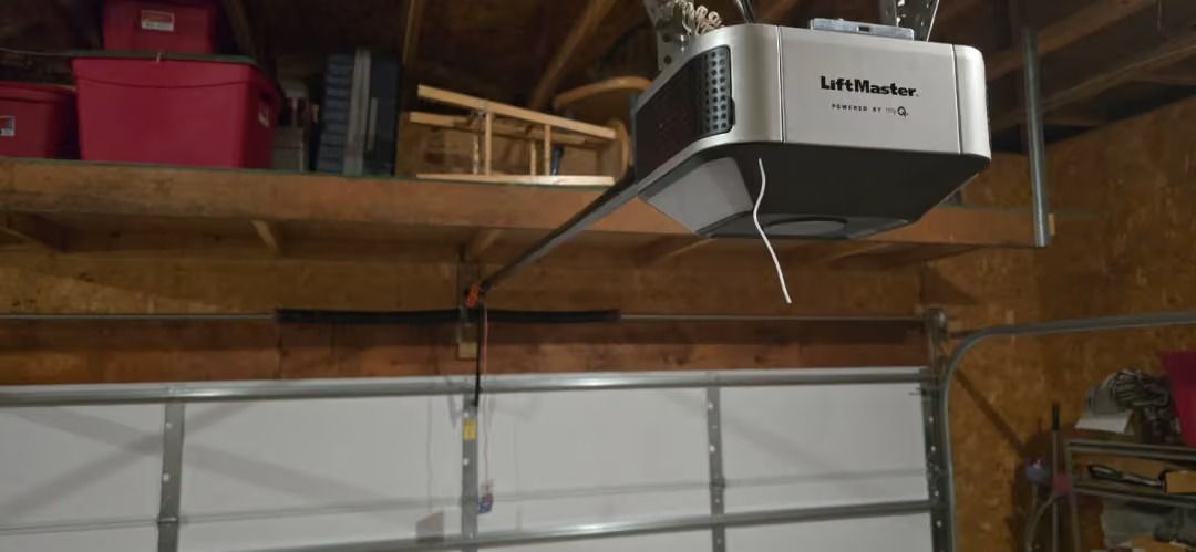 Garage ceiling with a mounted GDM? garage door opener above a closed white garage door