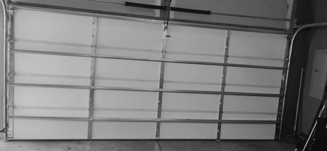 Closed white sectional garage door with dark trim in a dim interior setting