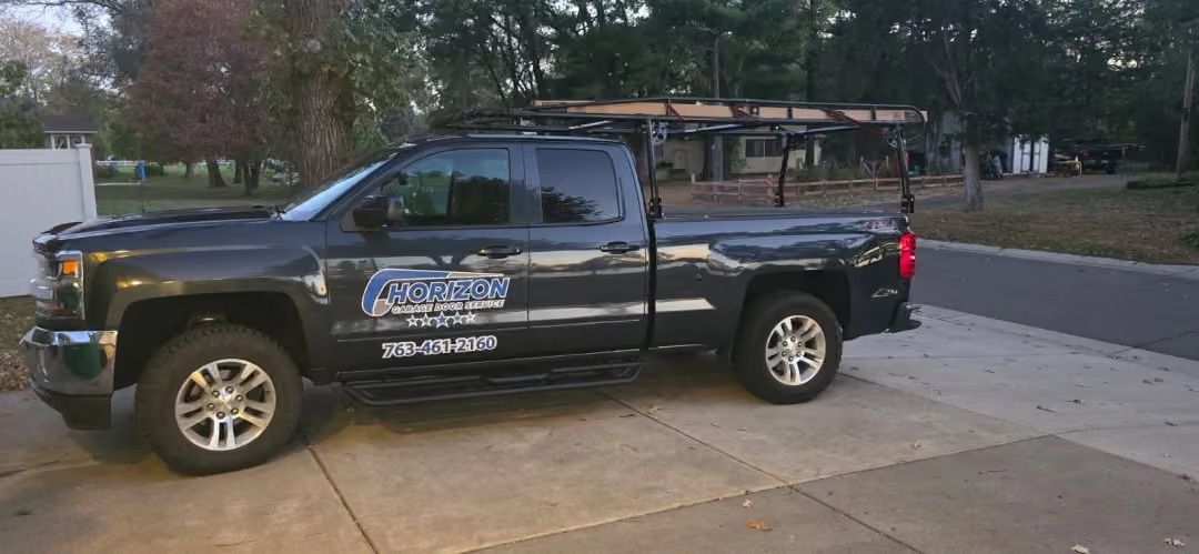 Black pickup truck with a company logo parked in a driveway at dusk.