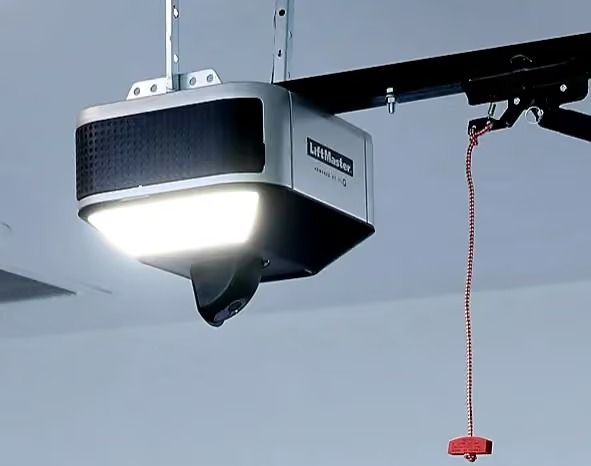 Overhead garage door opener with bright light and red pull cord hanging beside it