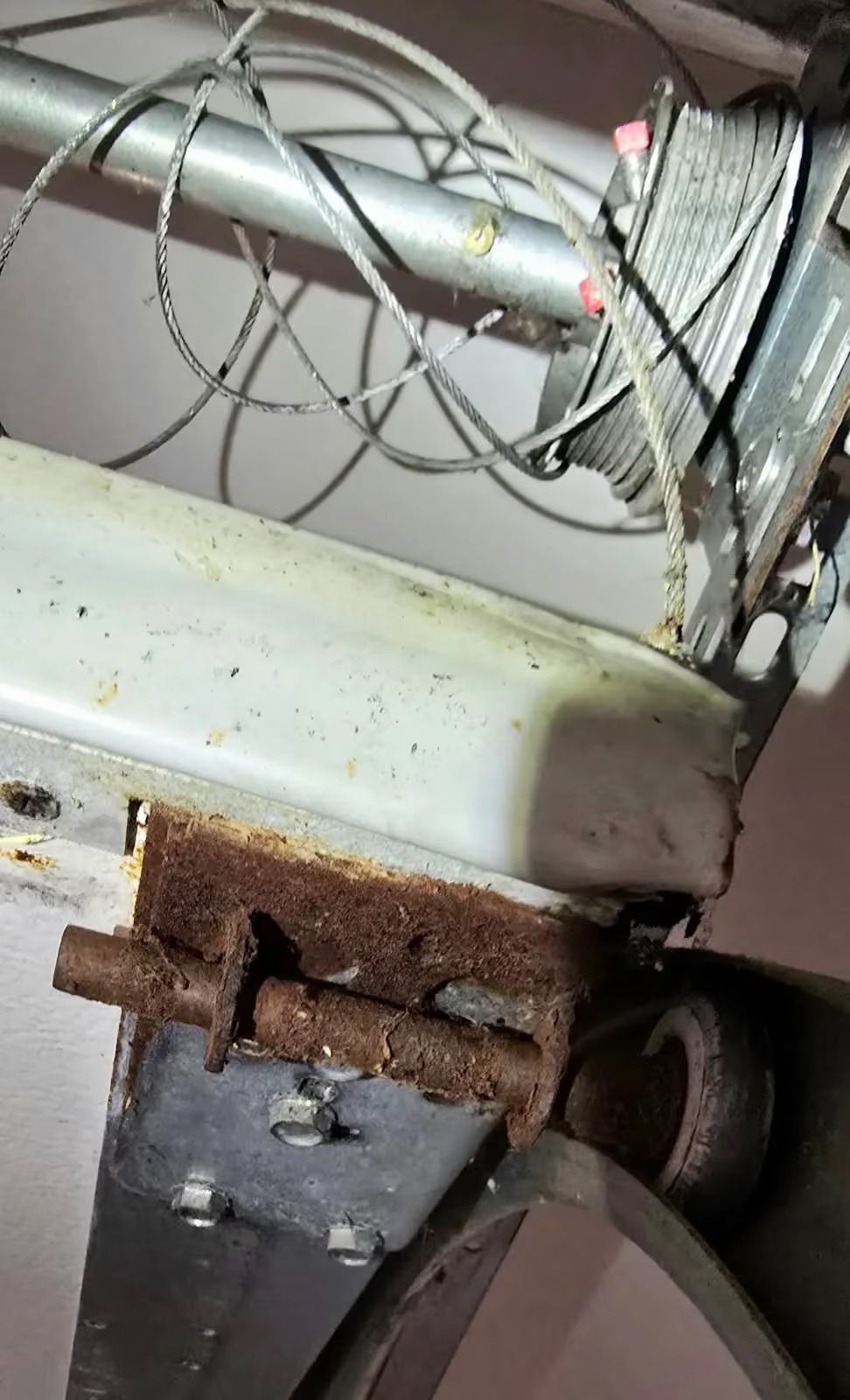 Rusty metal hinge and white appliance edge with coiled wire in a cramped mechanical space