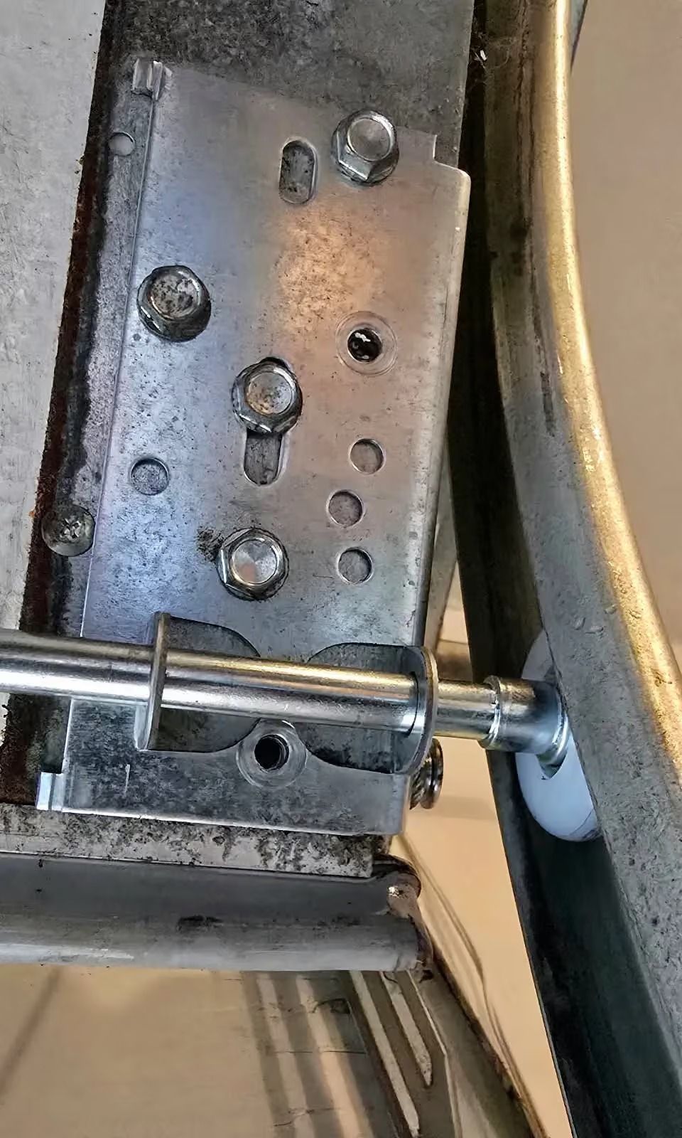 Close-up of a metal hinge latch and bolts on a gray industrial panel.