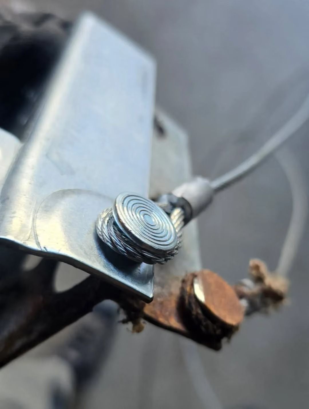 Close-up of a metal screw terminal with a wire attached to a bracket, showing rust and wear