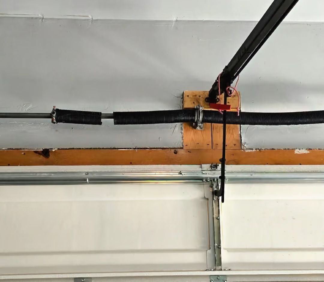 Garage door opener rail mounted on a ceiling, with black cable and orange bracket.