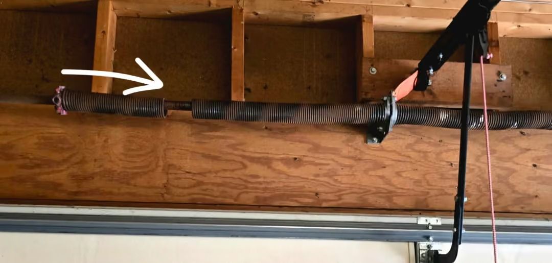 Arrow pointing to a black cable strapped along exposed wooden beams in an unfinished ceiling.
