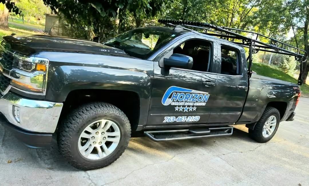 Black pickup truck with company logo parked on a driveway, side view with trees in the background