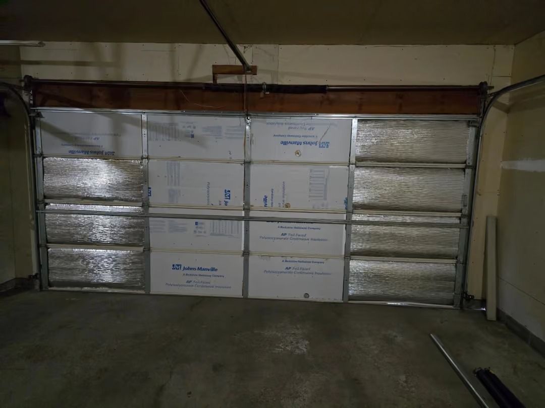 Stacks of boxed insulation blocking a garage door, with silver reflective wrap on both sides.