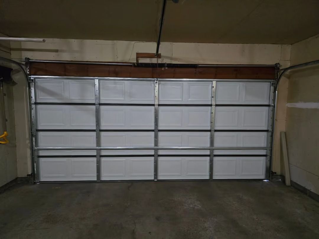 Empty garage with a closed white sectional door and concrete floor