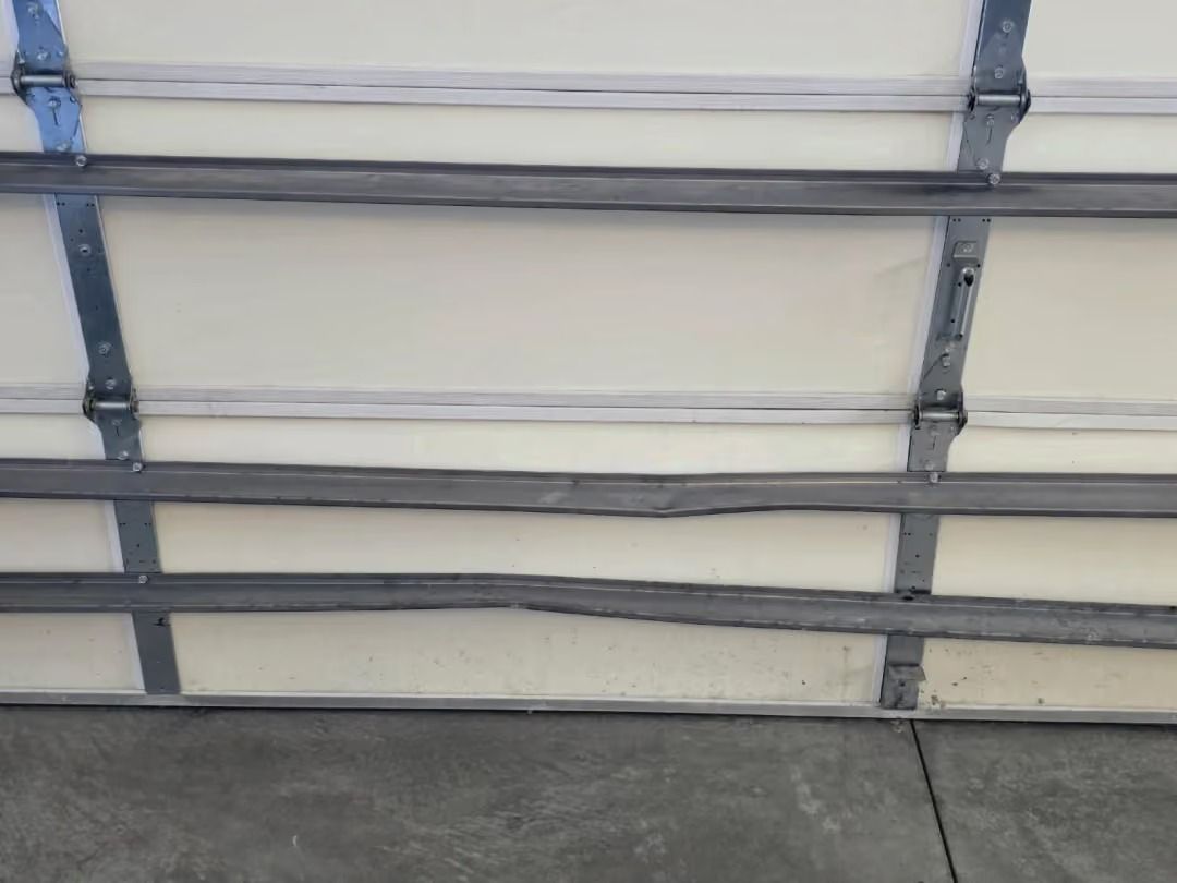 White garage door with horizontal gray panels above a concrete driveway.