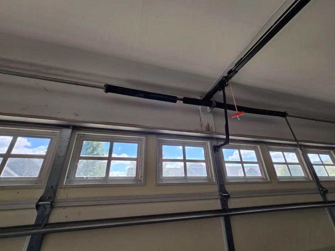 Garage door windows with a ceiling-mounted opener rail and hanging red cord.