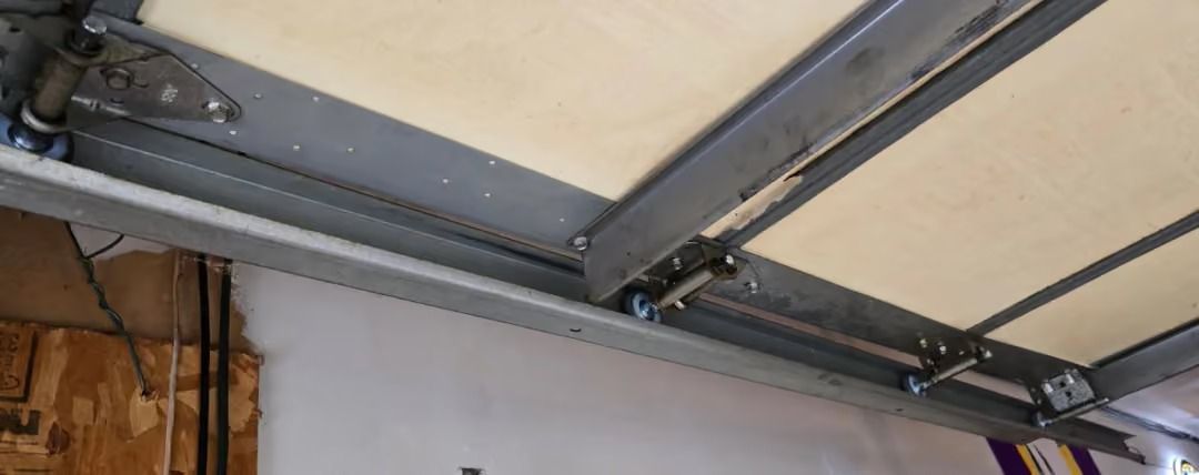 Garage ceiling with exposed metal tracks and a beige overhead door panel