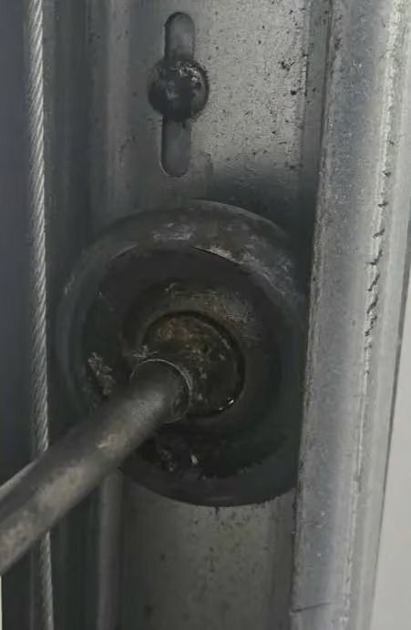 Close-up of a metal rod inserted into a worn door lock mechanism on a gray surface.