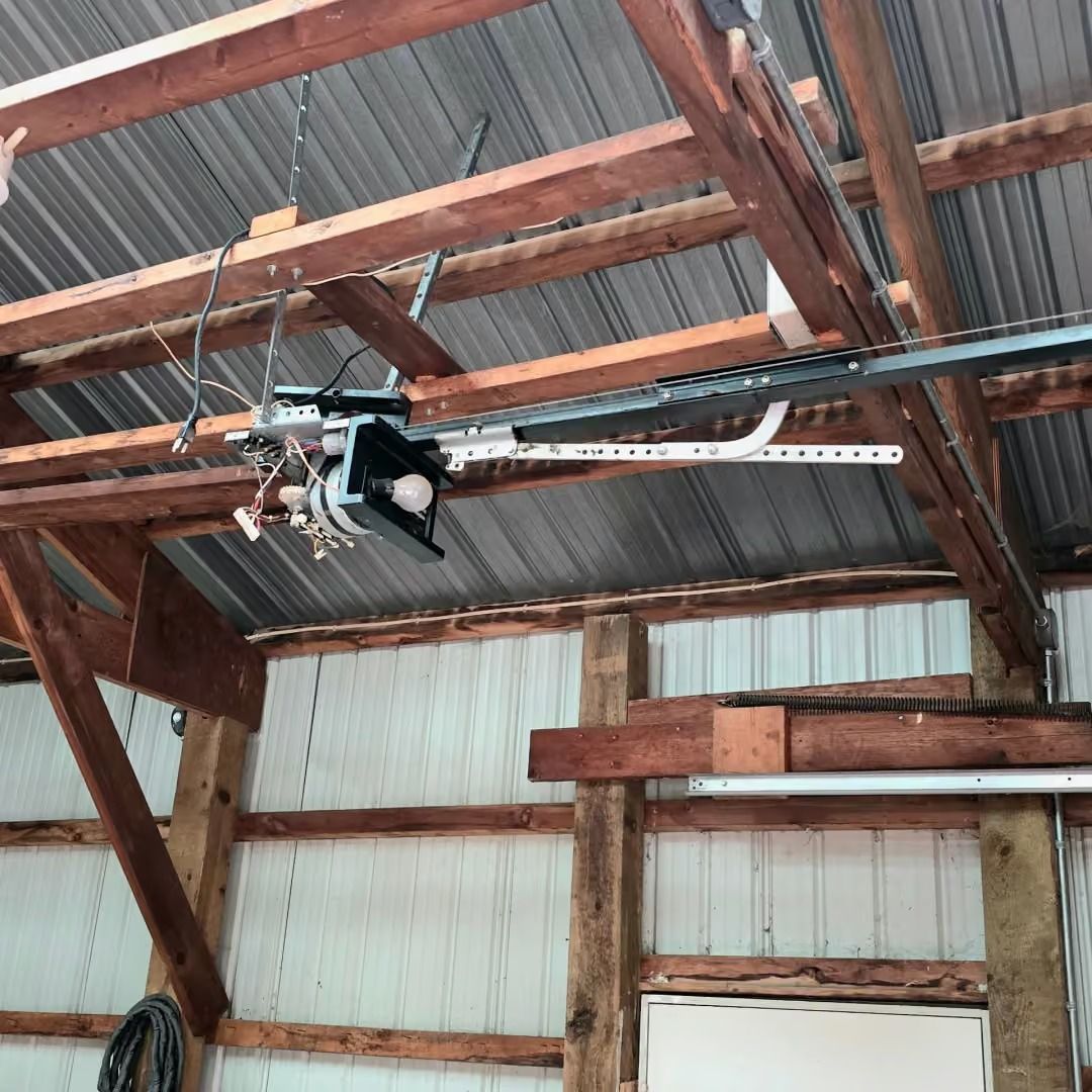 Garage ceiling with exposed wooden beams, corrugated metal roof, and a hanging garage door opener.