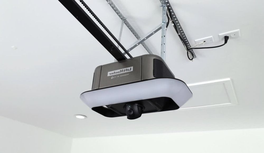 Ceiling-mounted black garage door opener with rail and wall switch in a white garage