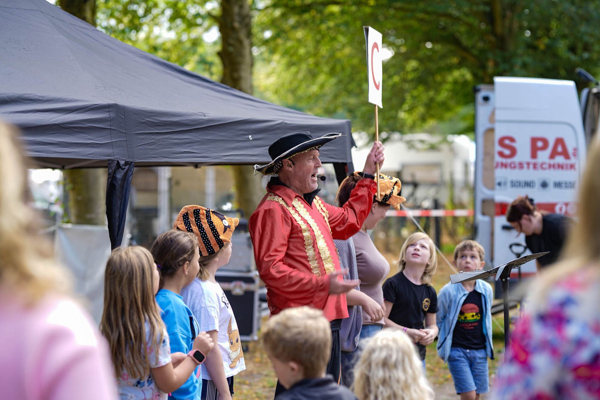 Cattu, der an einem Stand im Freien eine kleine Menschenmenge an Kindern unterhält