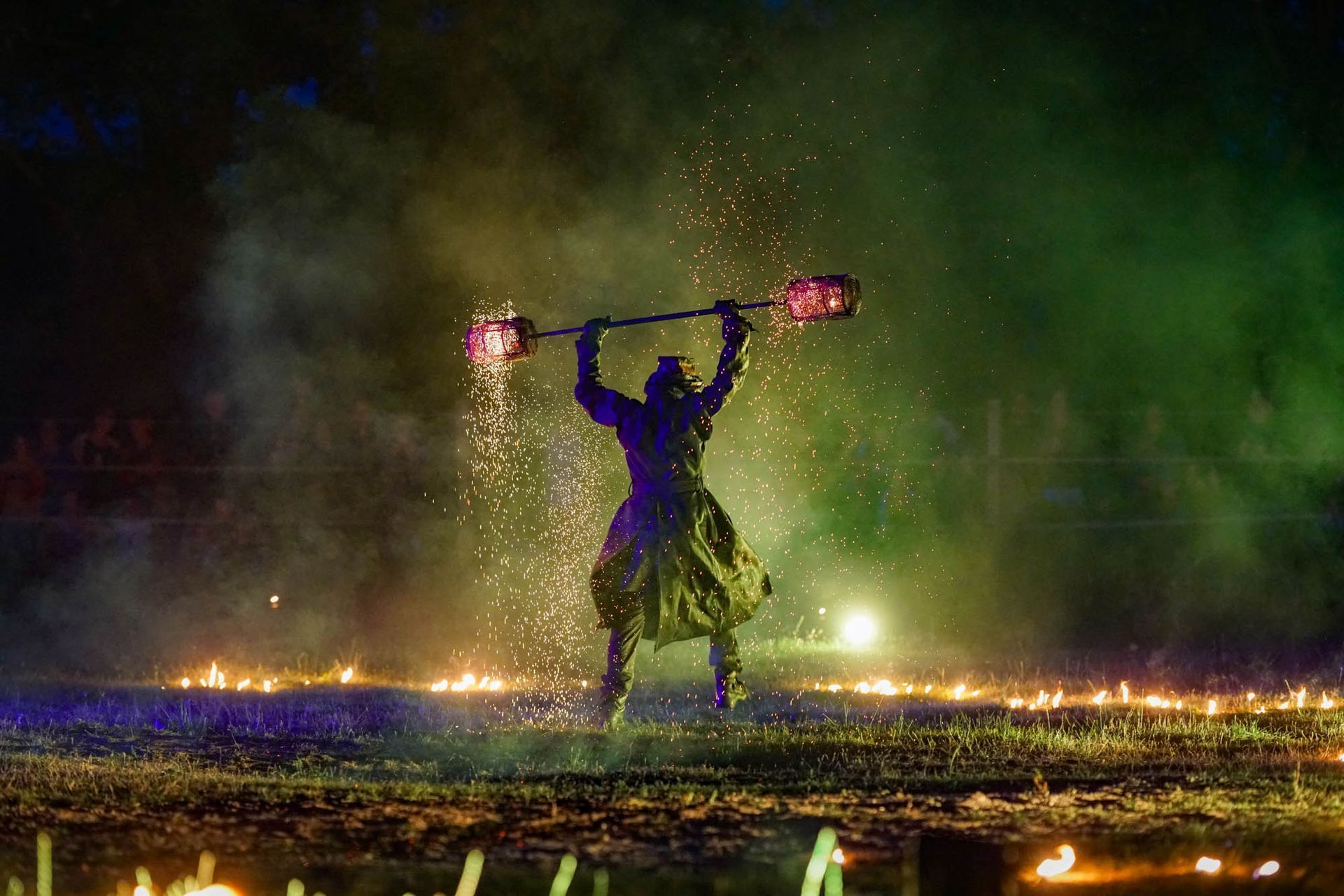 Silhouettenhafte Tänzerin in einem violetten Kleid mit Pompons unter bunten Bühnenlichtern und Nebel