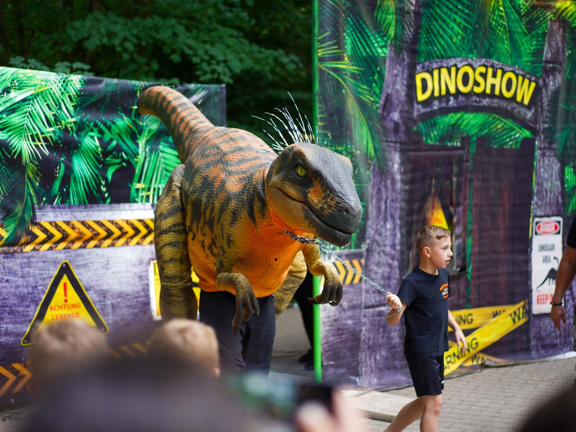 Dinosaurier interagiert mit einem Kind bei einer „Dino-Show“-Veranstaltung.
