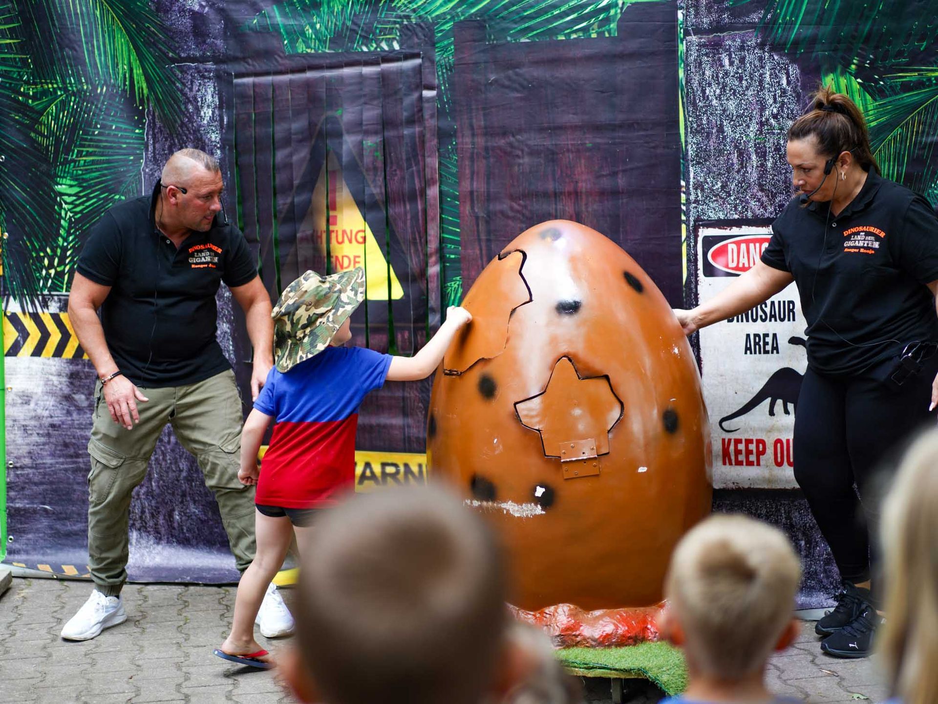 Kind berührt bei der Dino-Show ein großes Dinosaurier-Ei