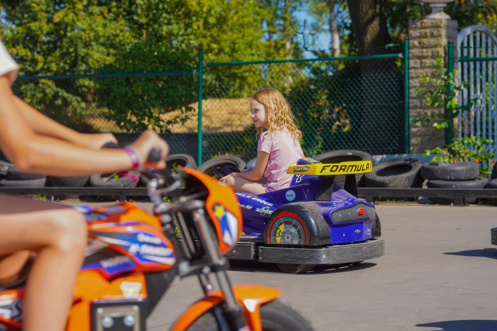 Ein Kind fährt auf einer Outdoor-Bahn ein lilafarbenes Autoscooter-Auto.