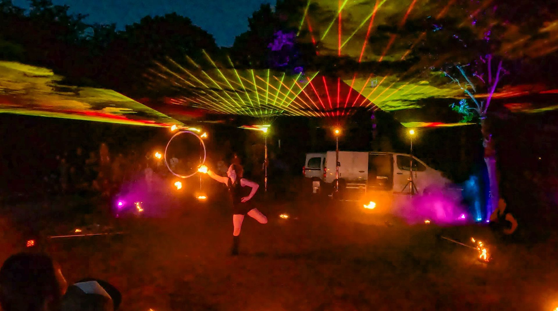 Eine Frau tanzt mit einem Hula-Hoop-Reifen im Freien mit bunten Laserlichtern