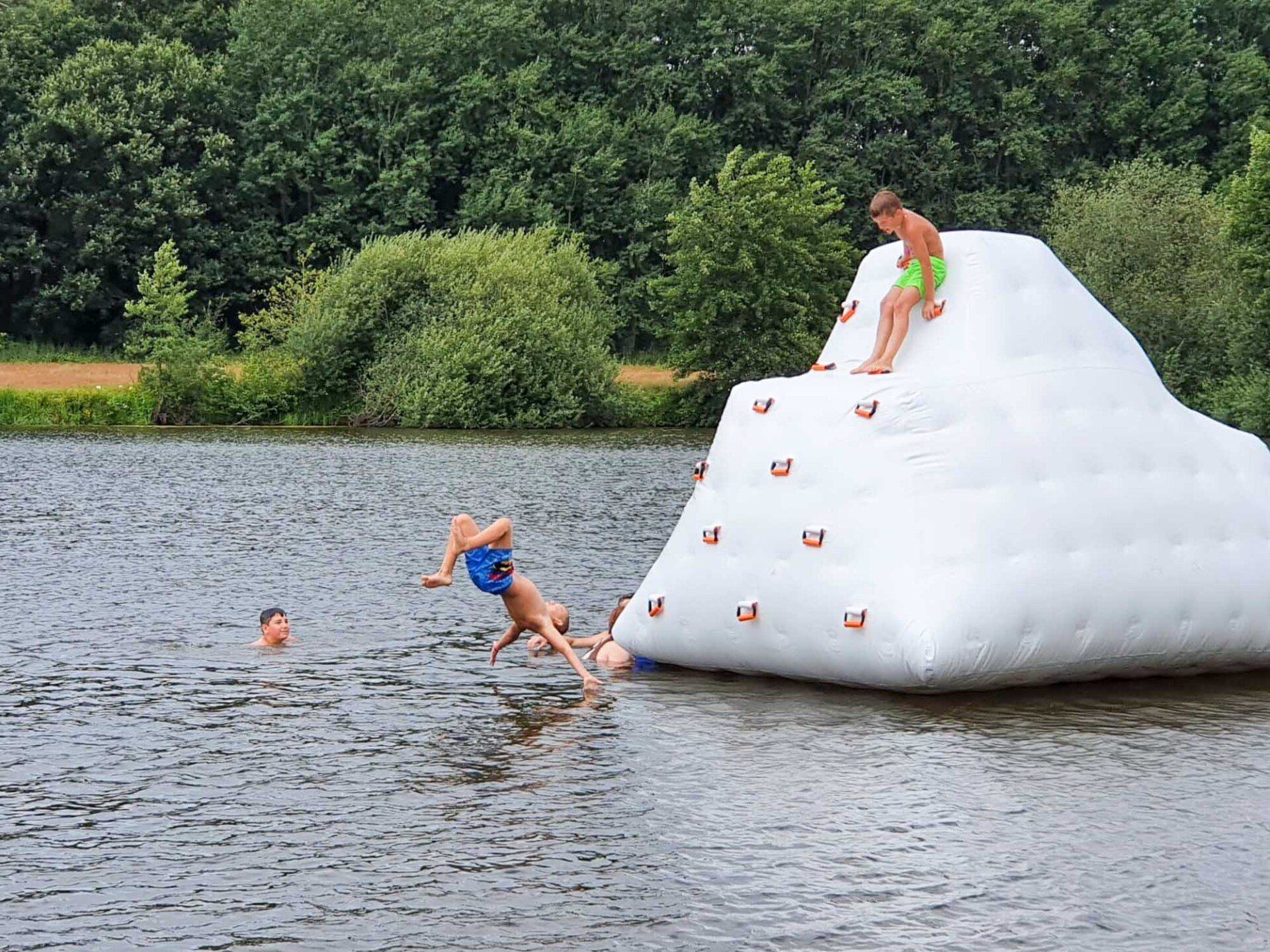 Kinder spielen auf einem weißen aufblasbaren Klettergerüst in einem See