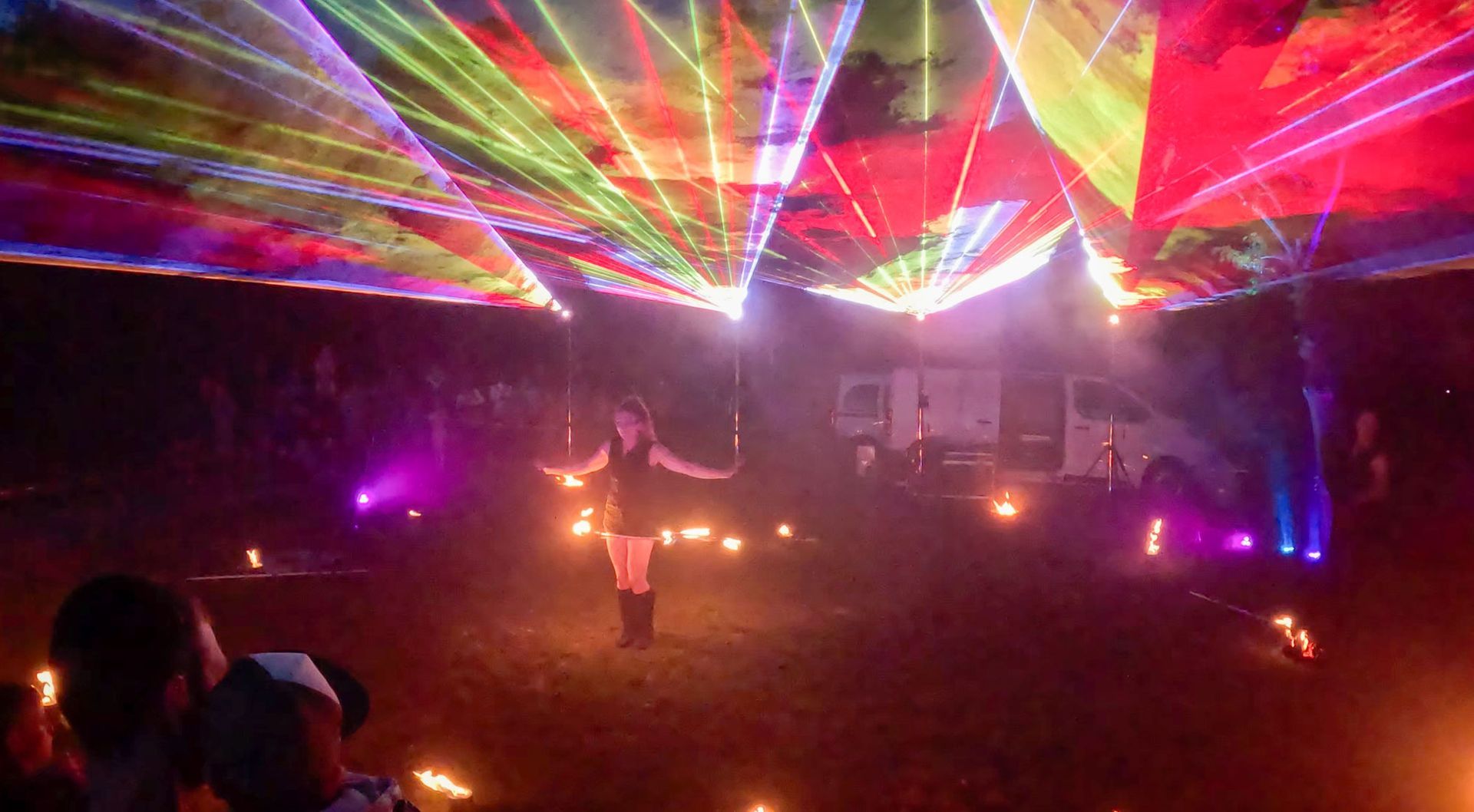 Frau tritt nachts im Freien unter buntem Laserlicht auf.