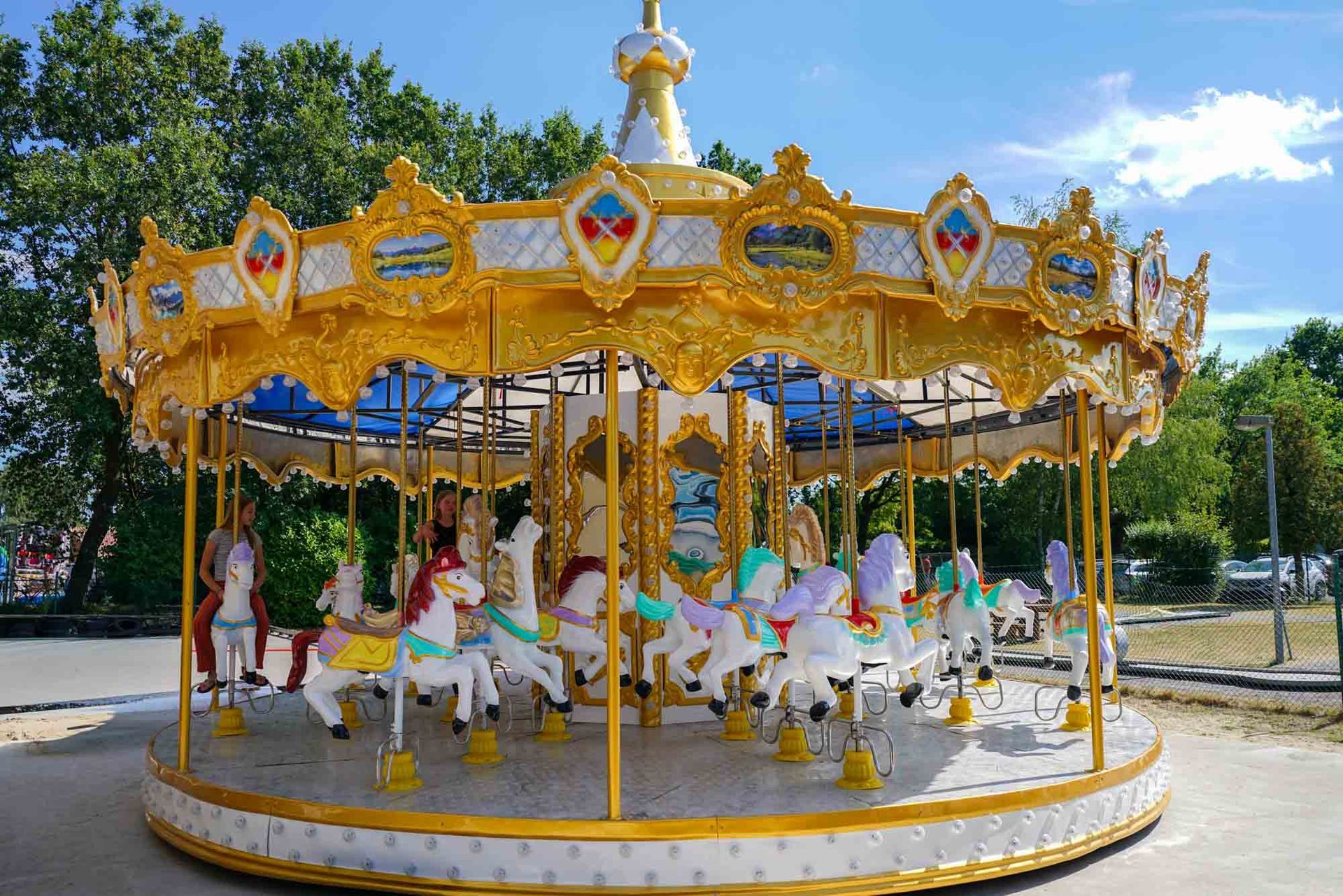 Gold-weiße Karussellpferde im Freien an einem sonnigen Tag
