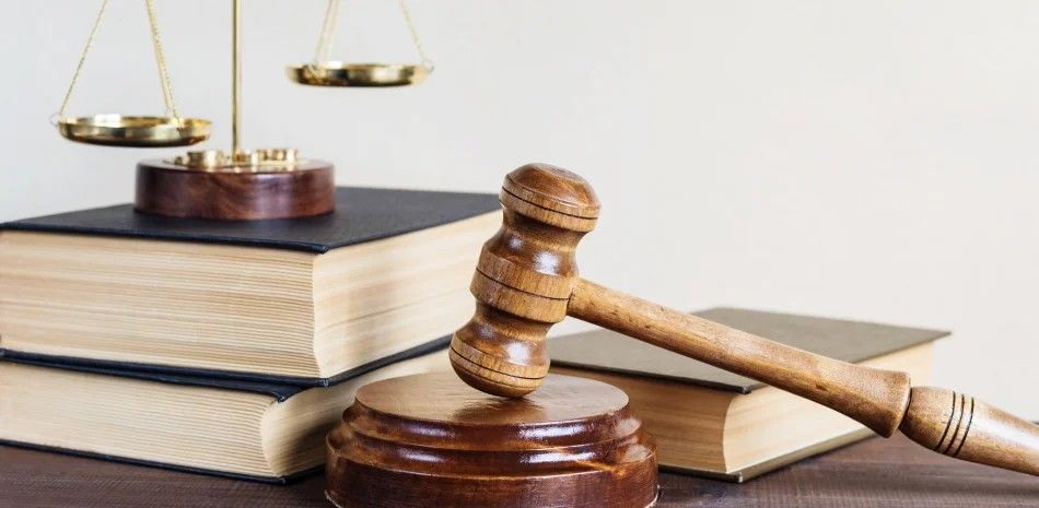 Judge’s gavel beside law books and scales on a desk