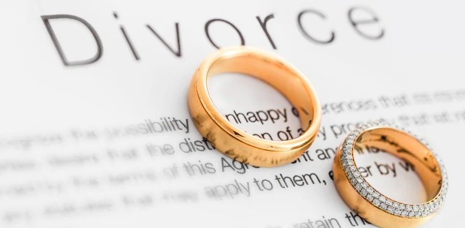 Two gold wedding rings on a divorce document