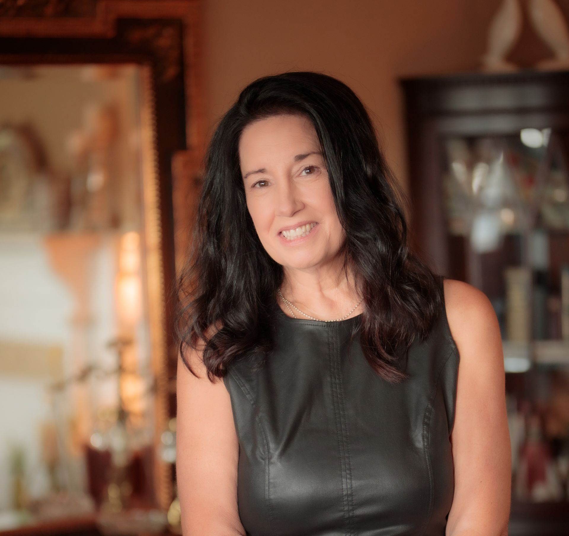 Smiling woman in a white blazer standing in a doorway indoors