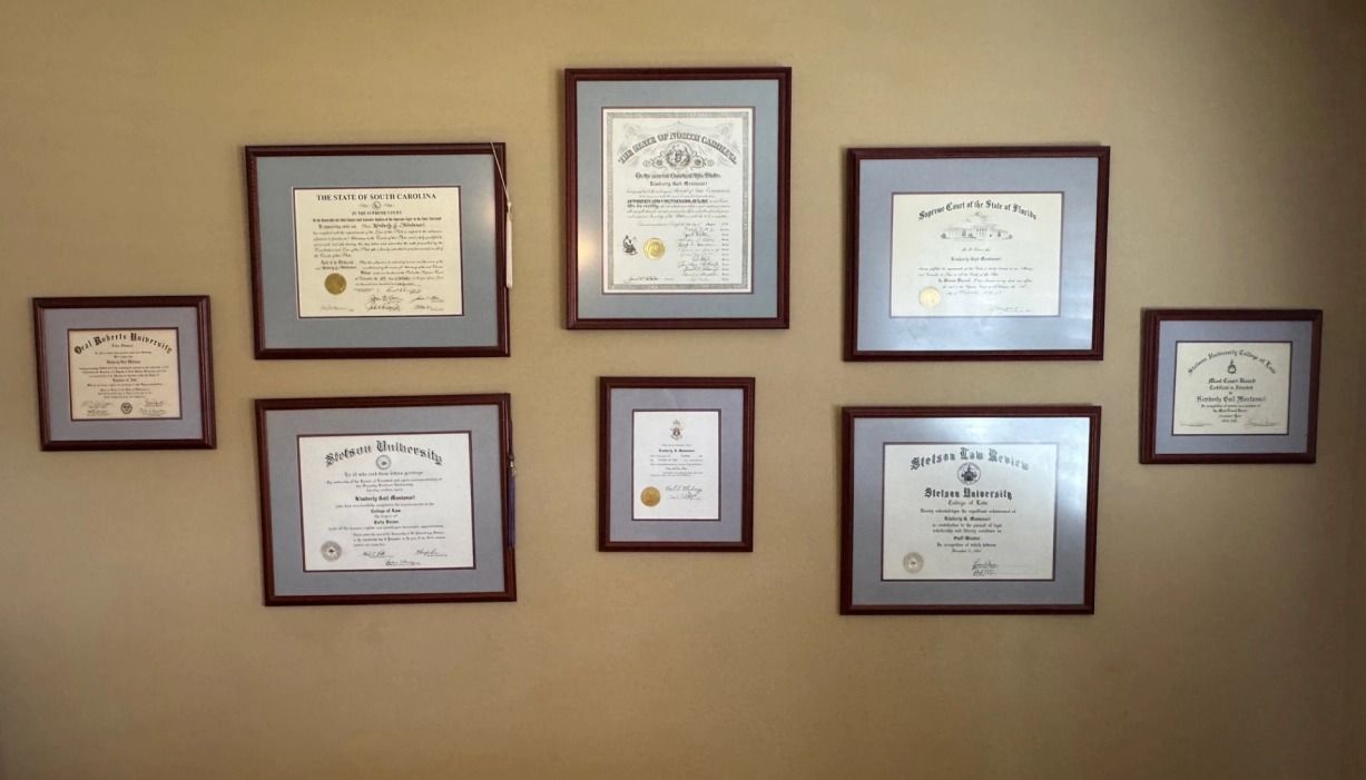 Seven framed certificates and awards arranged on a tan wall.