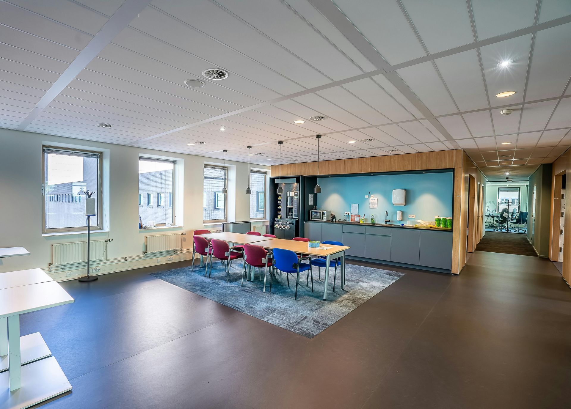 Modern conference room with colorful chairs, tables, a blue accent wall, and large windows