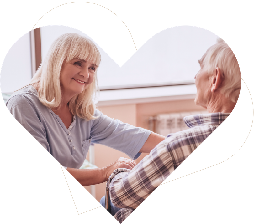 Caregiver smiling and holding hands with an elderly person in a heart-shaped frame