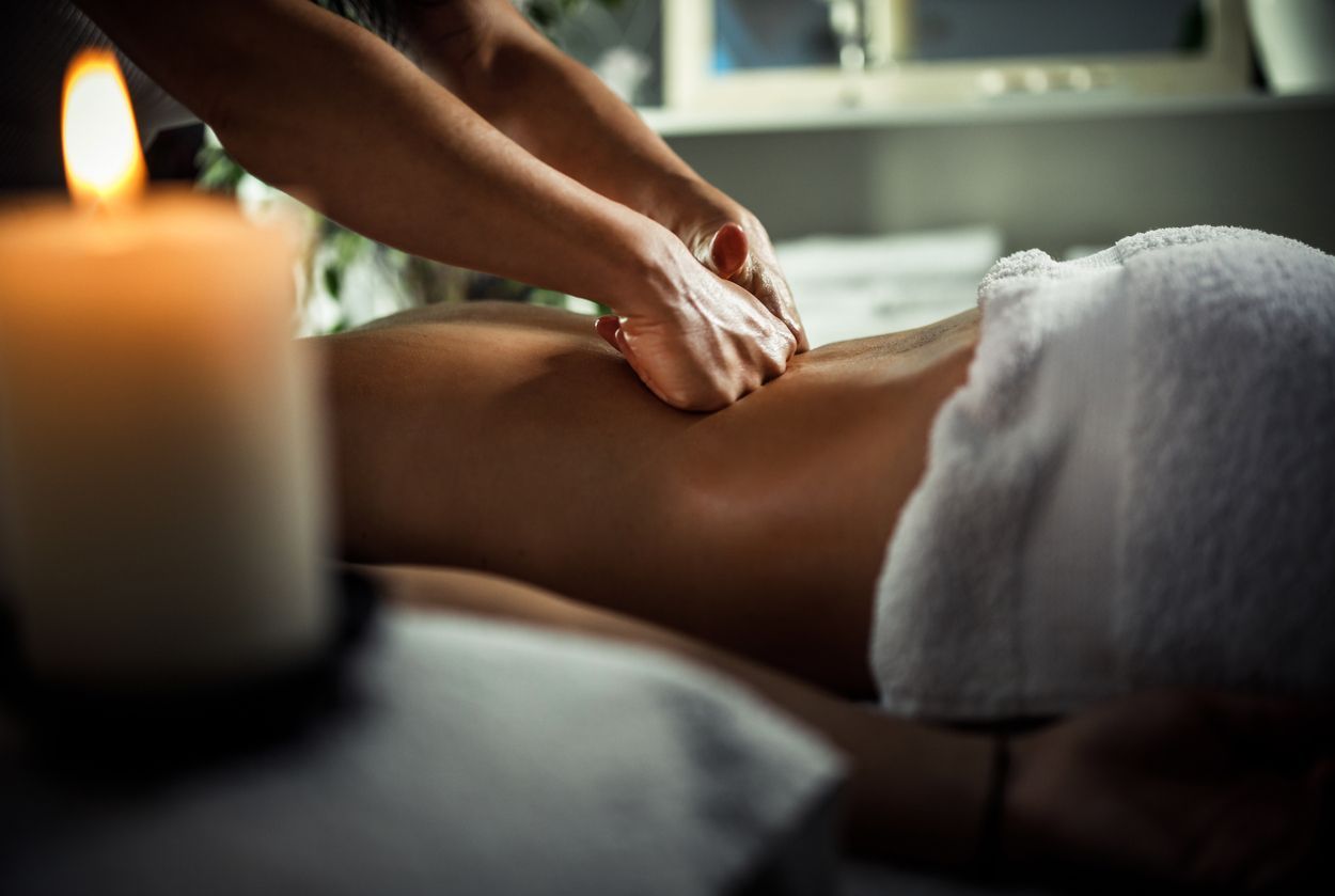 A woman is getting a massage in a spa with a candle in the background.